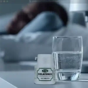 Melatonin kosttilskud på natbord ved siden af et glas vand i soveværelse
